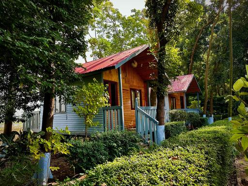 A cozy cabin nestled in a wooded area, surrounded by lush trees and bushes. Located near Dhaka Hotel in Savar's Barnochata resort.