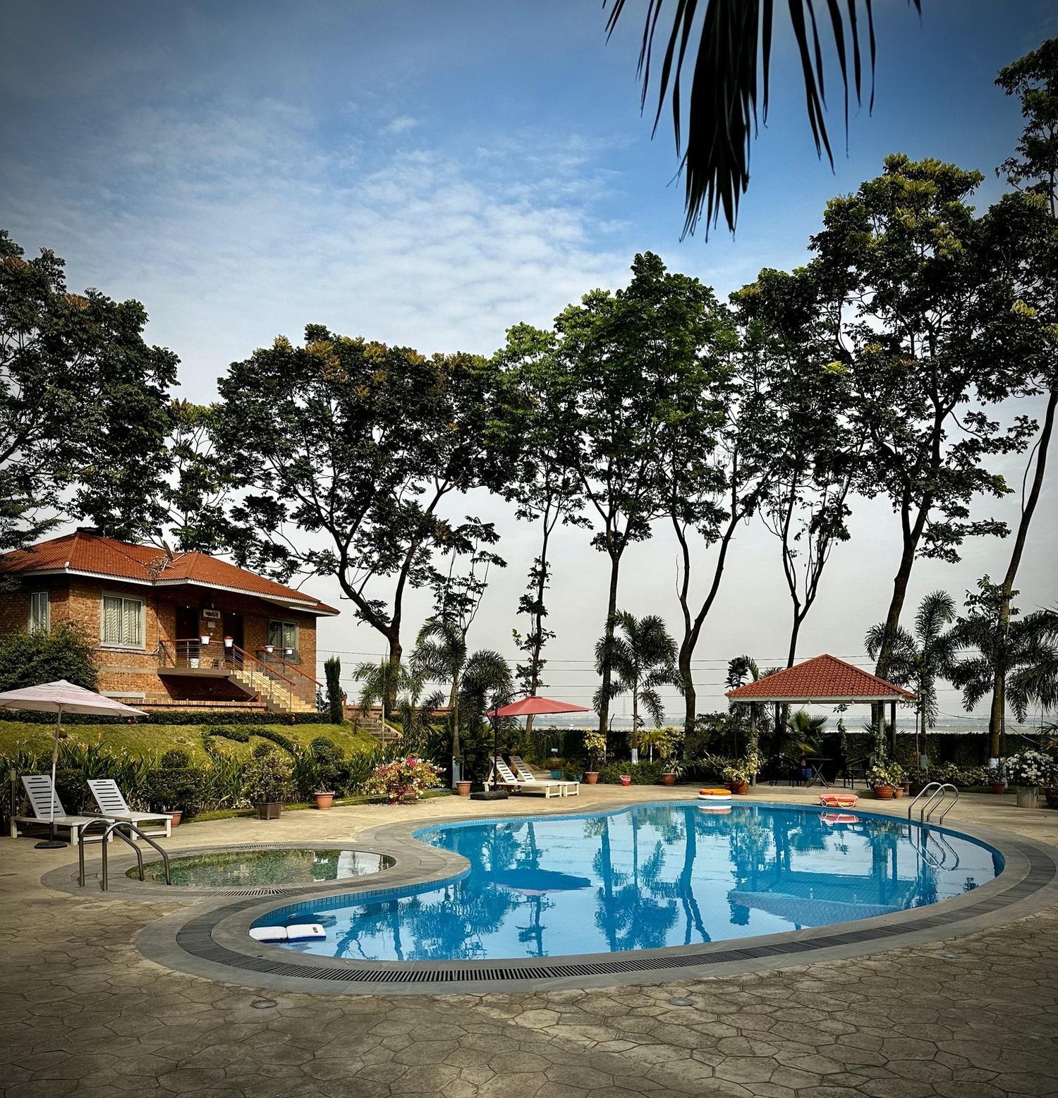Tranquil resort pool at a Barnochata Dhaka hotel in Savar, surrounded by lush greenery and traditional architecture, reflecting relaxation and luxury