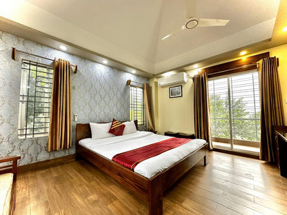 A cozy bedroom in Dhaka hotel with a comfortable bed, a ceiling fan, and a wooden floor.