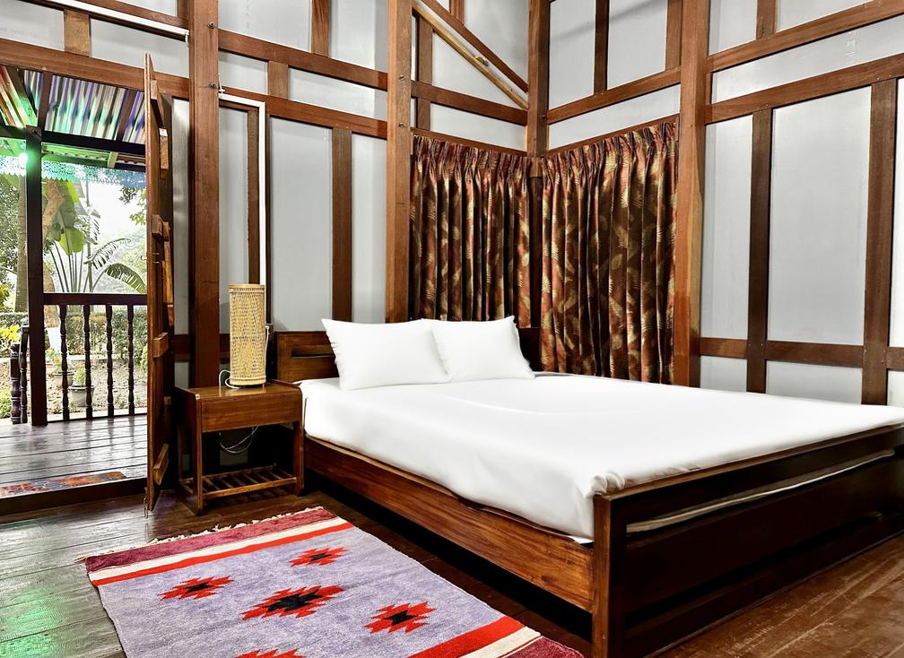 A cozy bedroom with wooden walls and a ceiling fan at the Dhaka Hotel, Barnochata Resort, Savar.