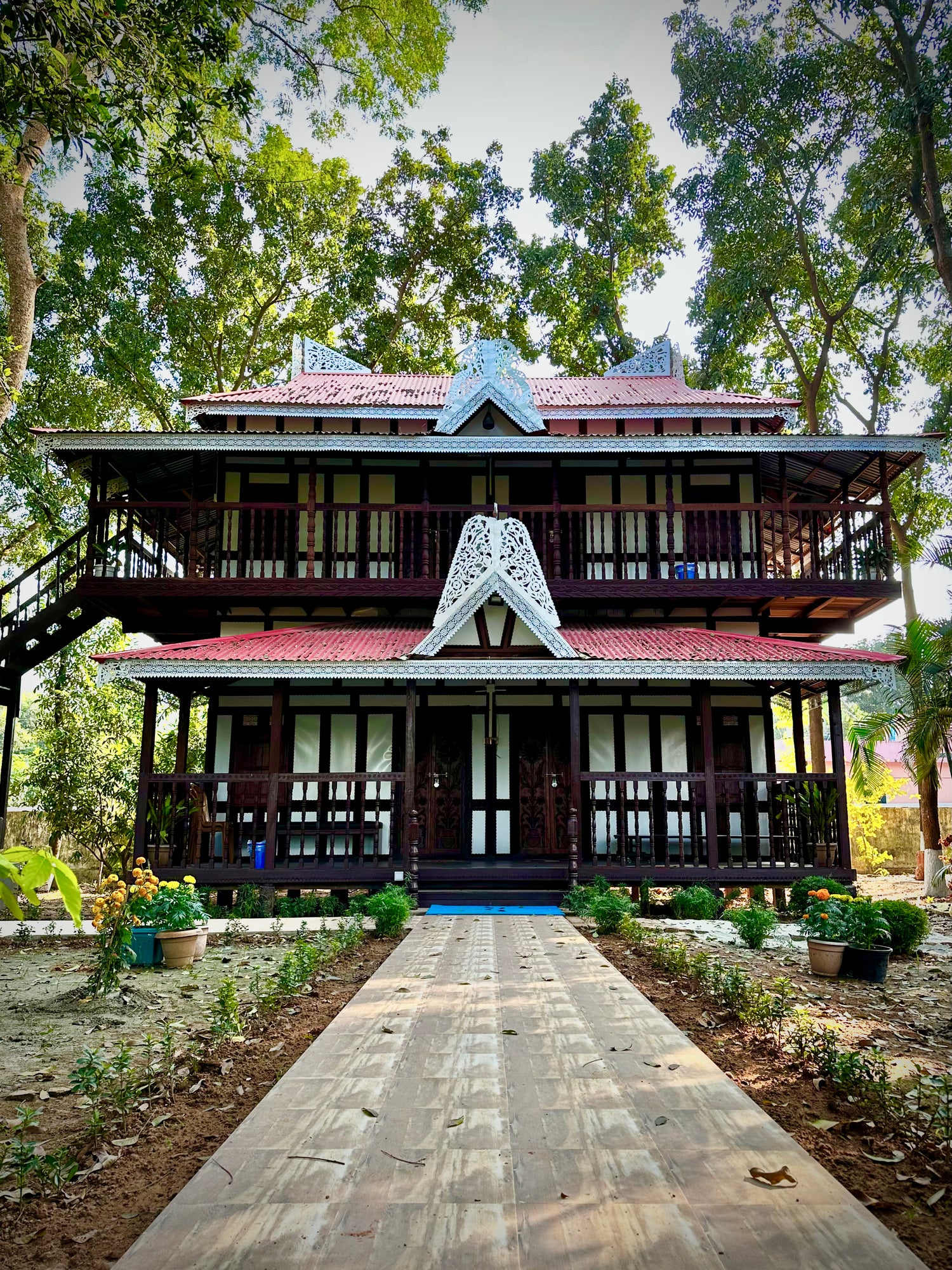 Traditional elevated Japanese wooden cottage at Barnochata, a Dhaka hotel and resort in Savar, set amidst lush greenery with a wooden walkway.
