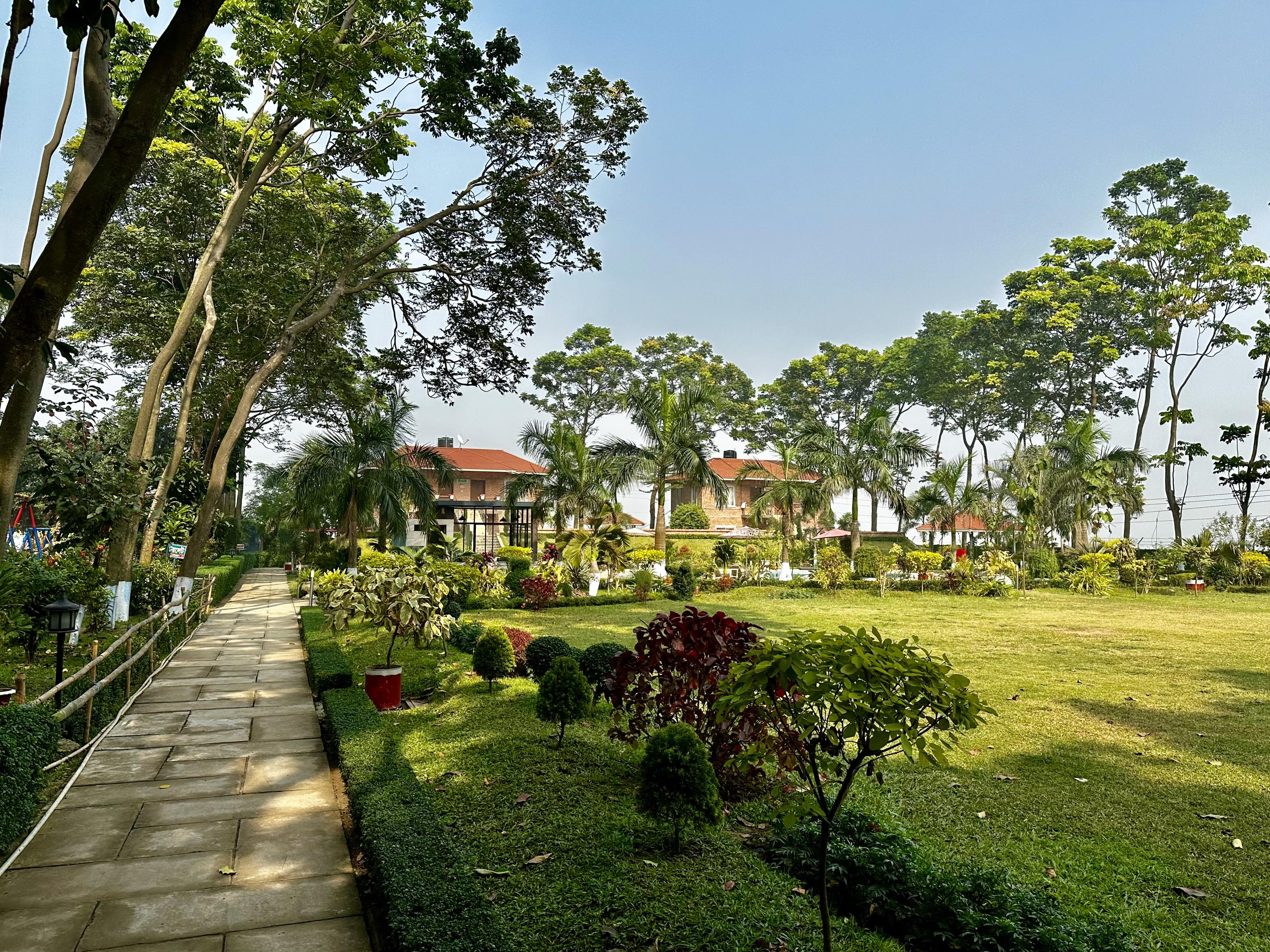 Scenic garden pathway leading to cottage-style accommodations at a lush Barnochata resort near Dhaka, located in Gazipur, a prime Dhaka hotel destination
