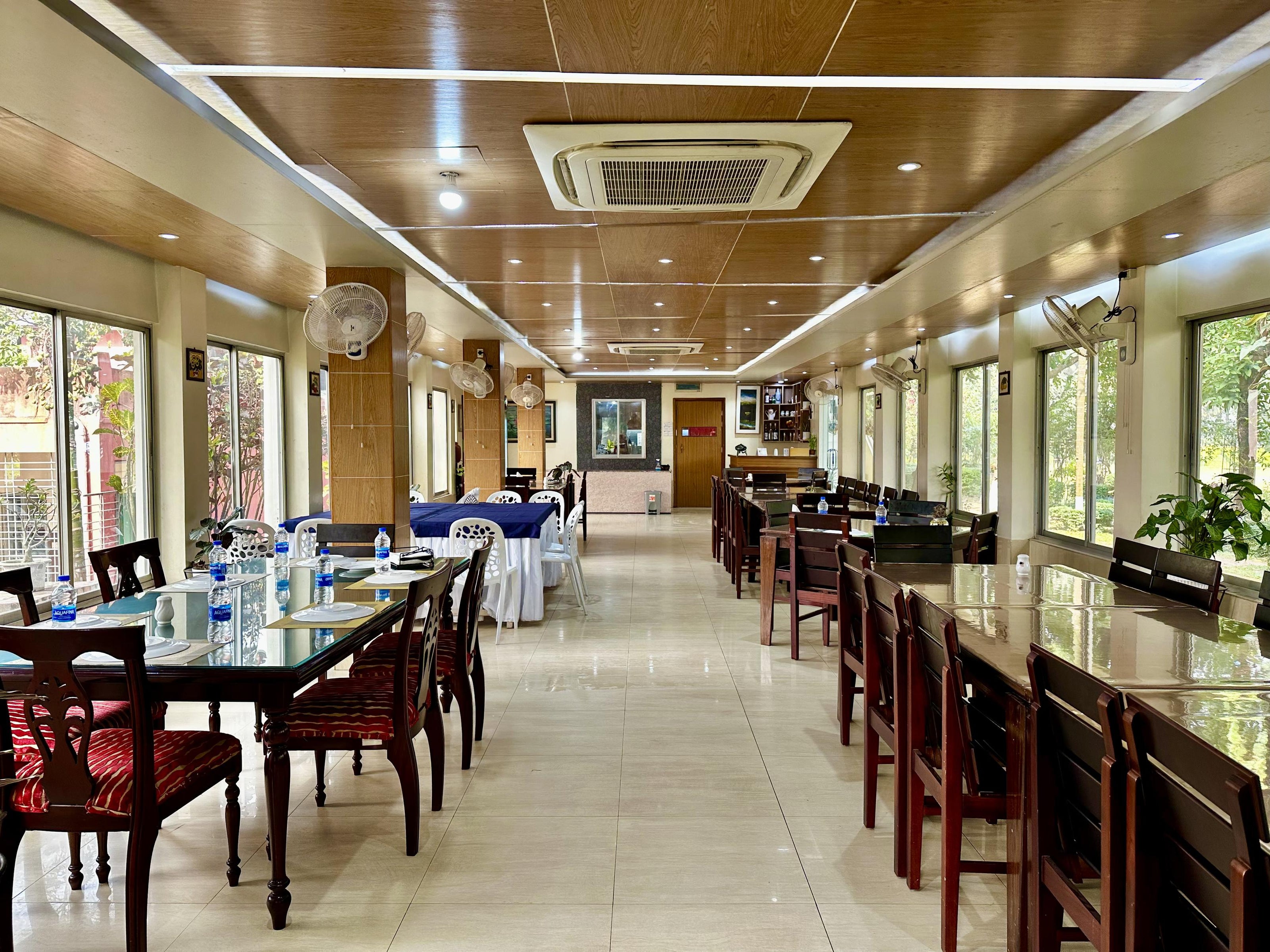 Elegant dining hall with large windows at Barnochata, a resort in Savar, offering a fine dining experience in a Dhaka hotel setting.