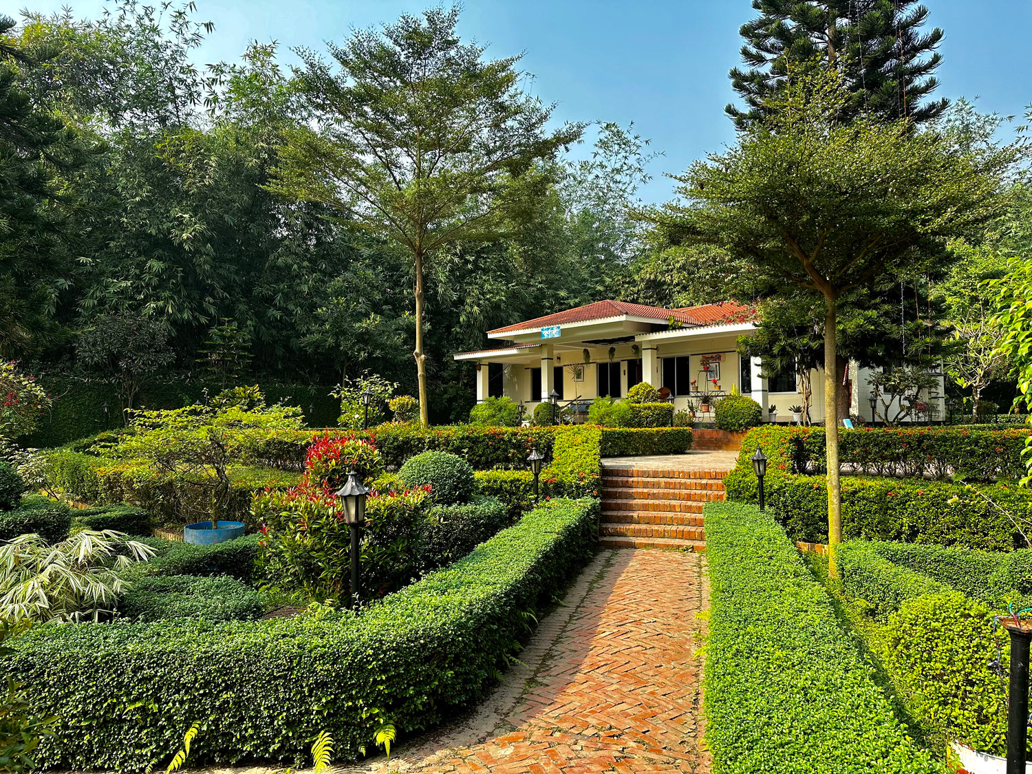 Beautifully landscaped gardens at Barnochata, a premier resort and Dhaka hotel located in Savar, featuring manicured hedges and a welcoming brick pathway.