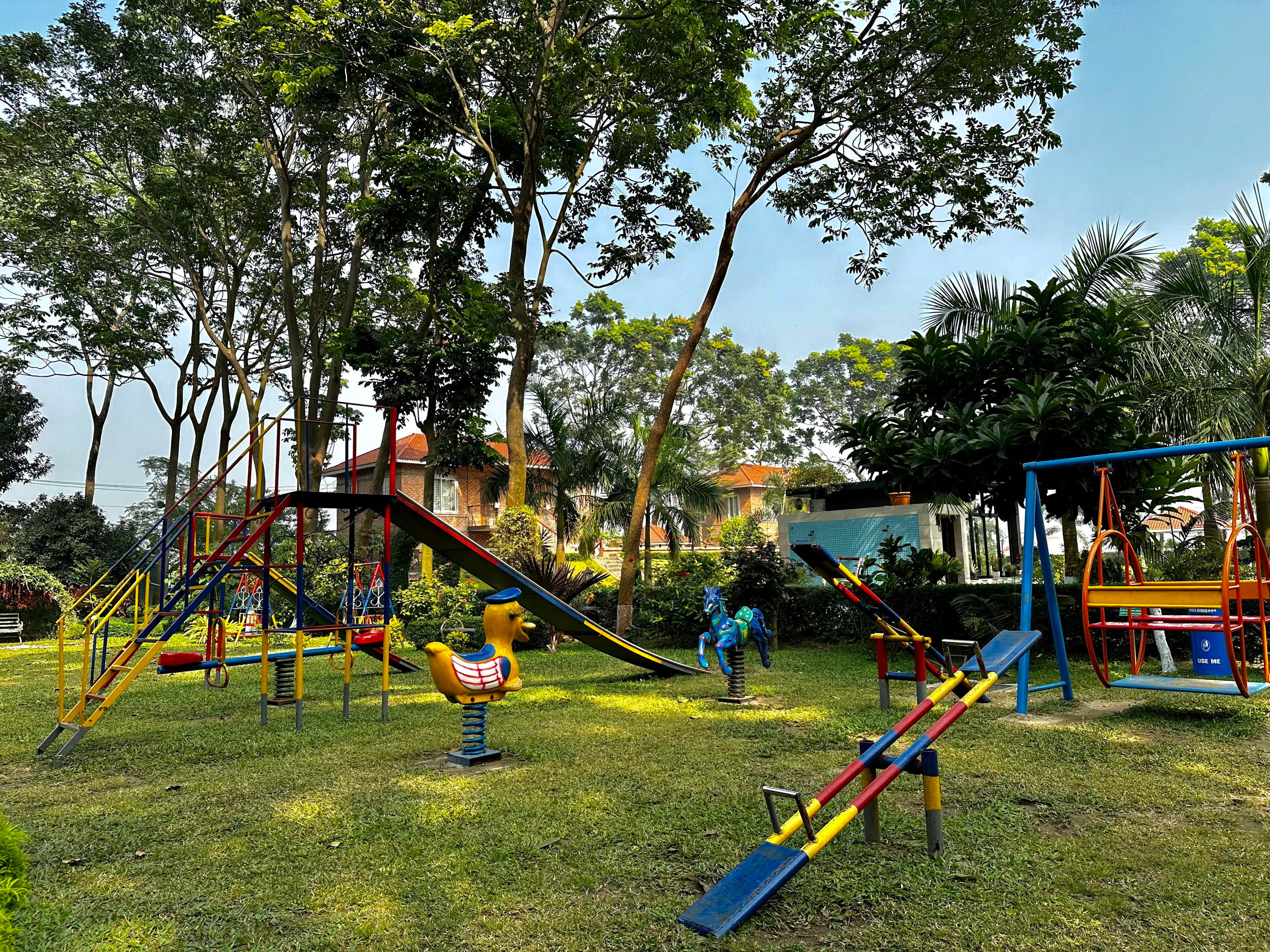 Colorful children's playground in the lush gardens of Barnochata, a family-friendly Dhaka hotel and resort in Savar.