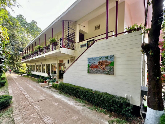 A scenic road leading to a building surrounded by lush plants and trees near Dhaka Hotel in Savar, Barnochata.